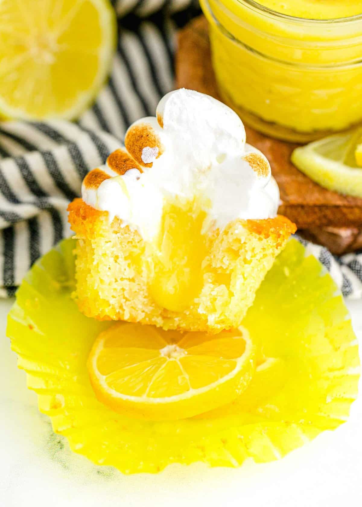 Bitten lemon meringue cupcake, showing lemon curd filling