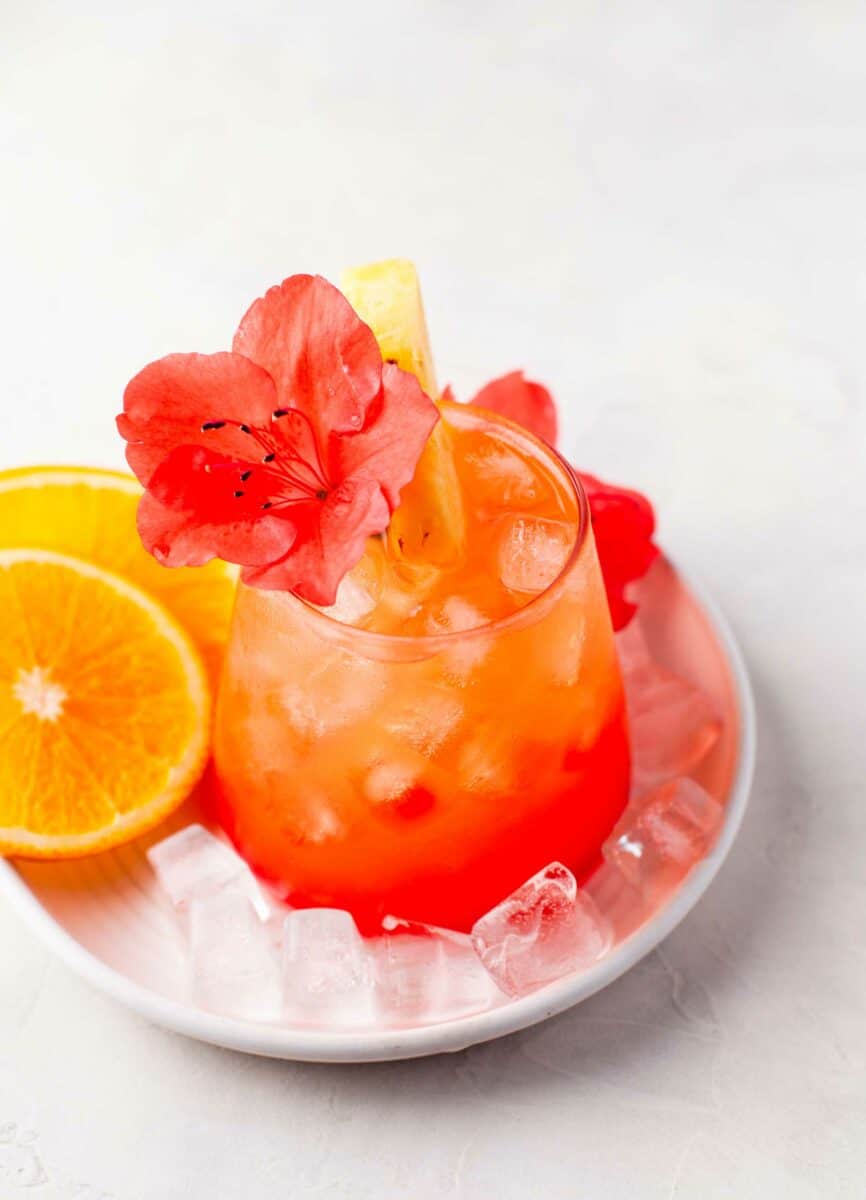 A garnished glass of punch is surrounded by orange slices. 