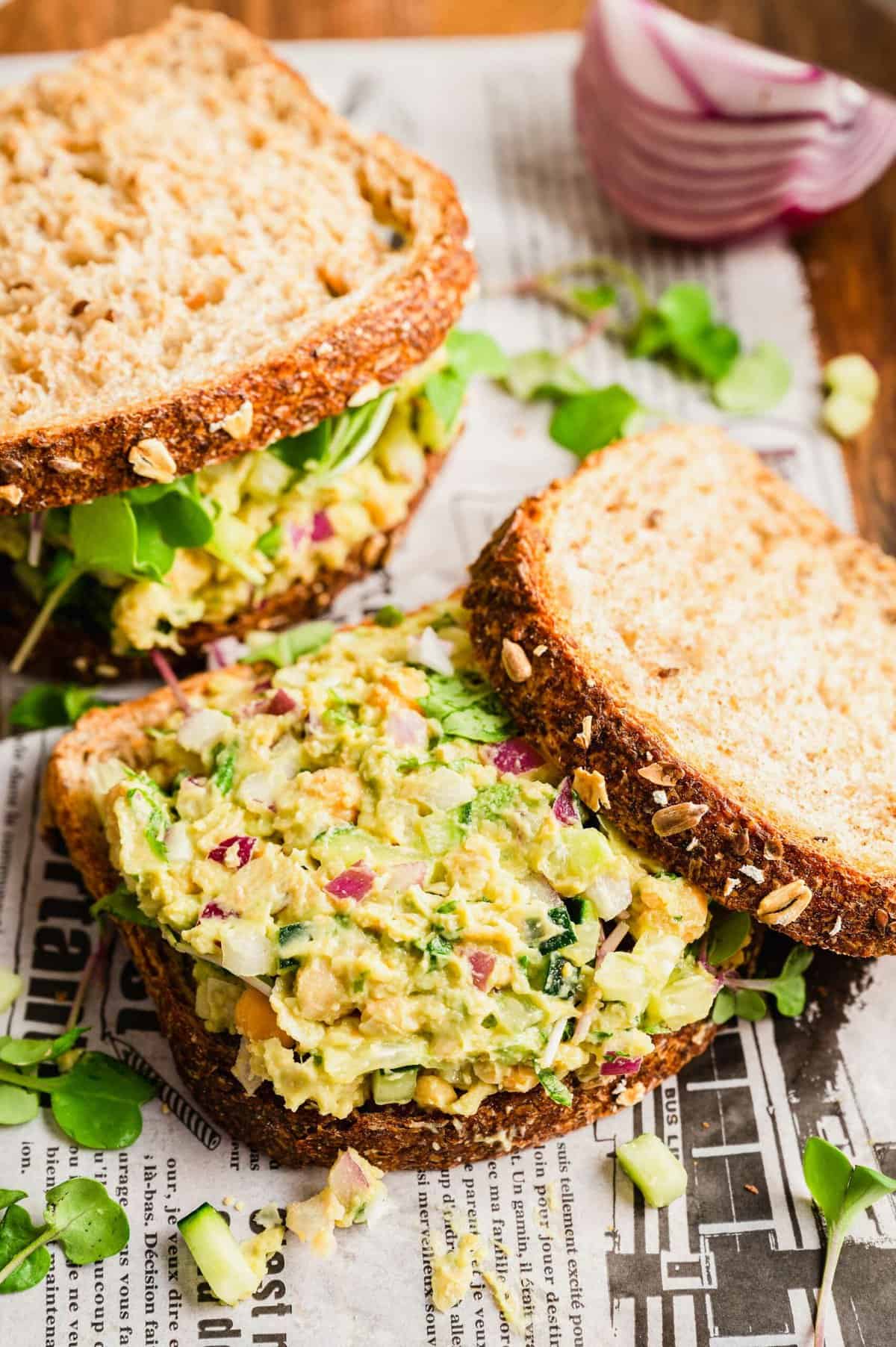 Two smashed chickpea sandwiches, one open to show filling