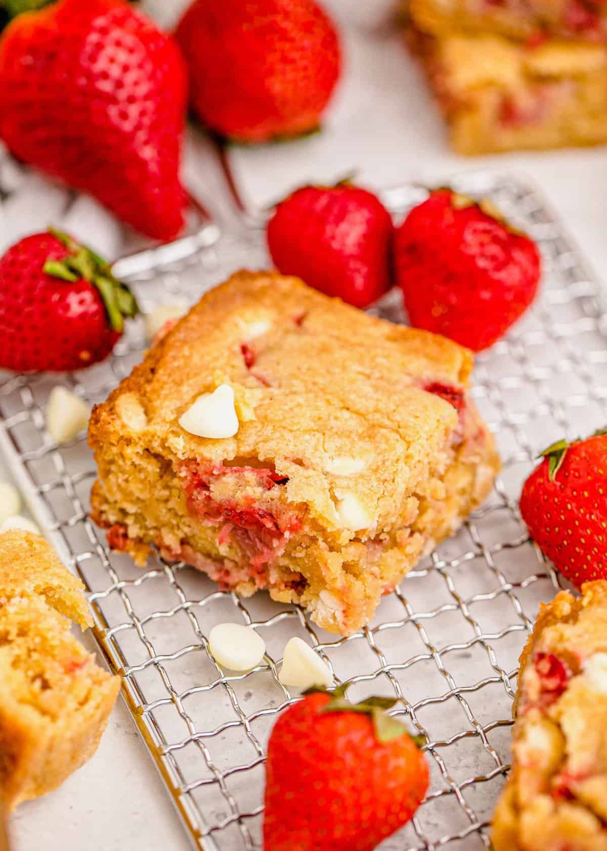 Strawberry blondie on cooling rack with fresh strawberries
