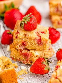 Two stacked strawberry blondies surrounded by fresh berries