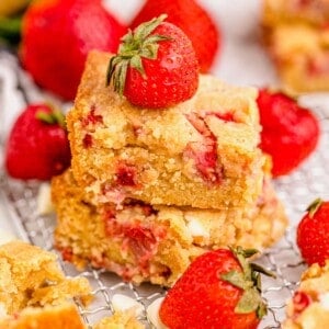 Two stacked strawberry blondies surrounded by fresh berries