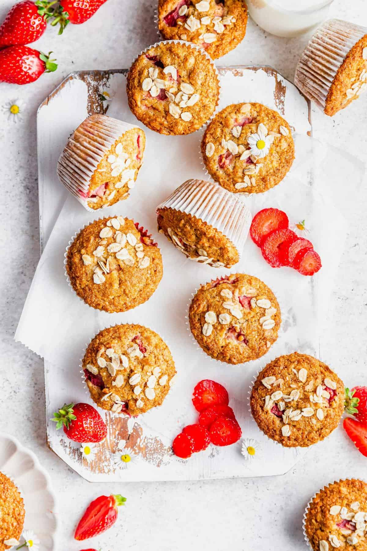 Overhead view of strawberry oatmeal muffins on rustic wooden board with fresh strawberries
