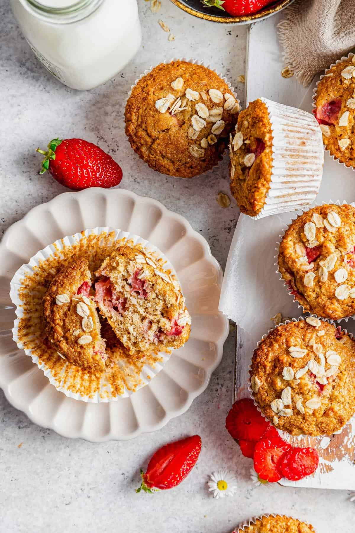 Overhead view of strawberry oatmeal muffins on plate and board