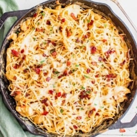 baked chicken spaghetti in a cast iron skillet with fresh parsley on top