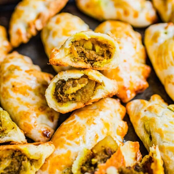 Chinese curry pockets on baking sheet, with some cut open to show filling