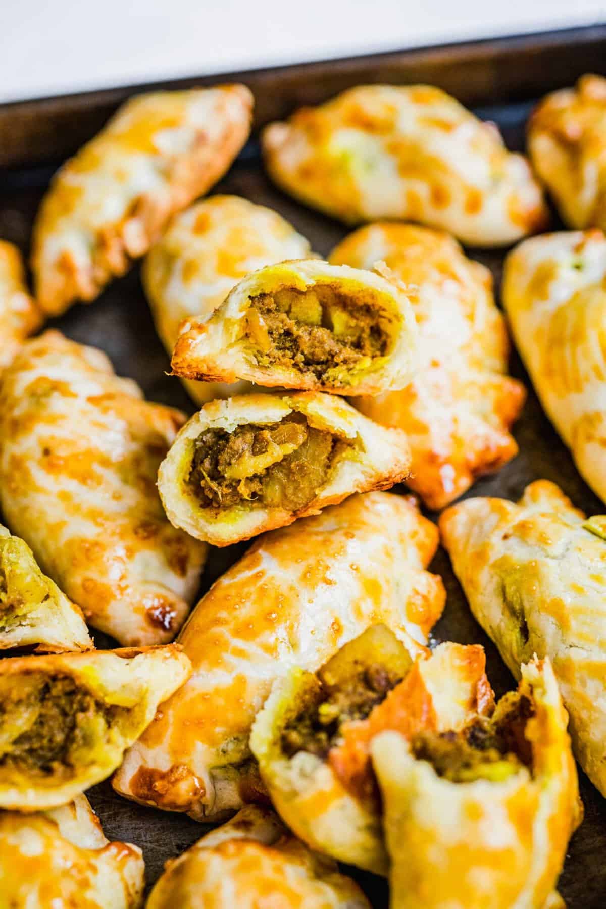 Chinese curry pockets on baking sheet, with some cut open to show filling