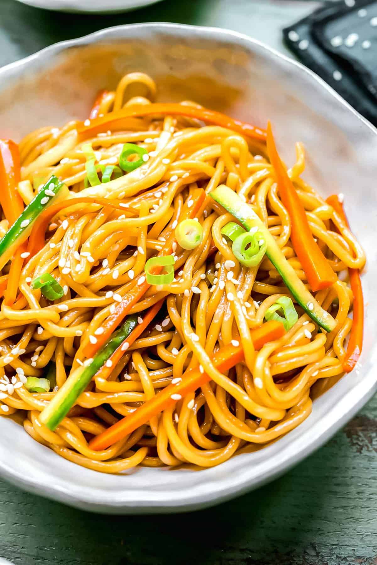 These cold sesame noodles are so easy to put together on a hot day! Made with fresh noodles and crisp veggies tossed in umami-rich sauce. Sesame noodles in a bowl garnished with sesame seeds.