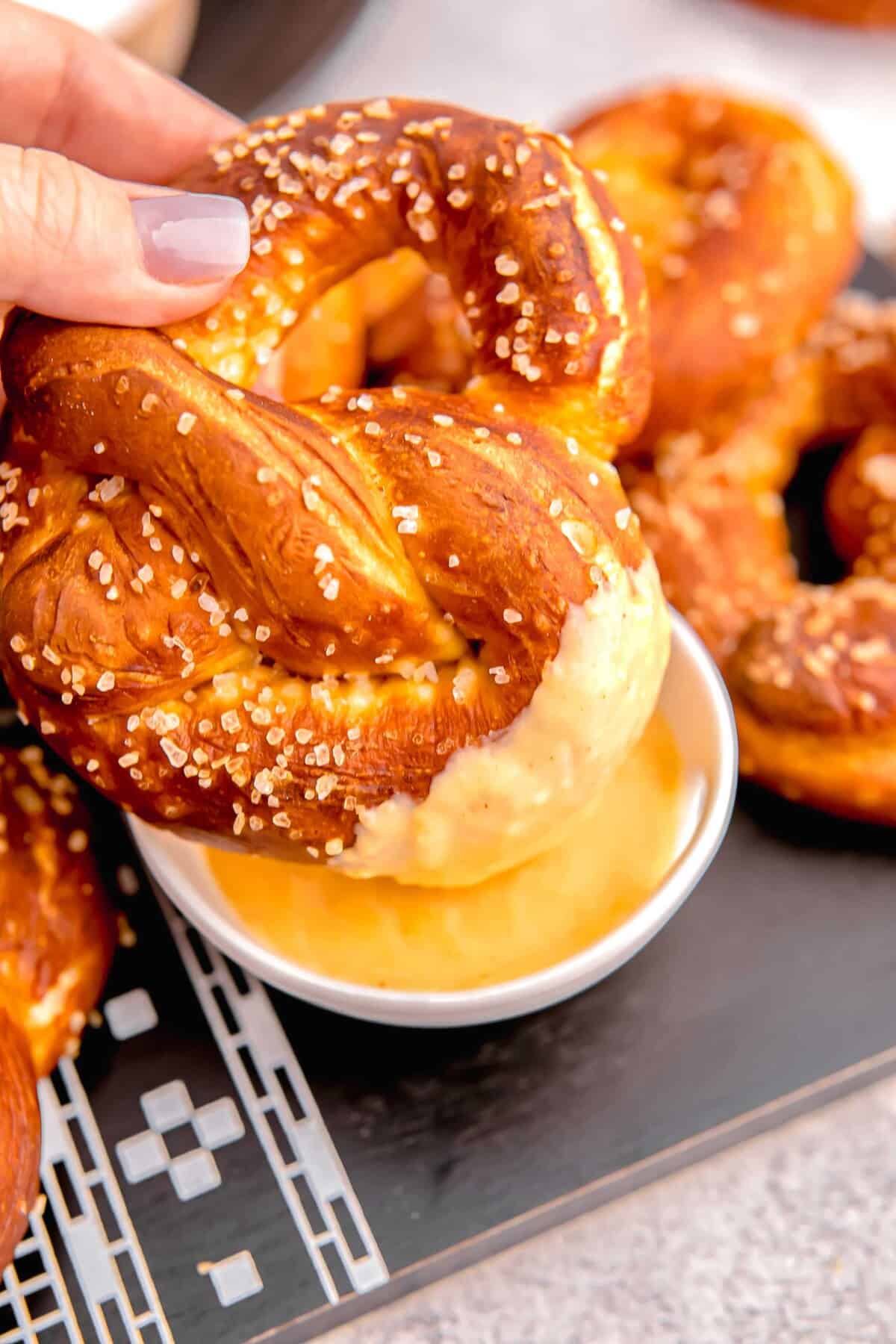 dipping soft pretzel into beer cheese dip