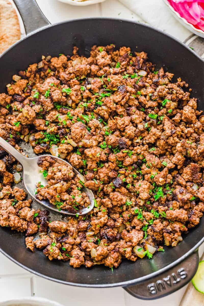 Vibrant green parsley is garnishing a pan filled with cooked ground beef. 