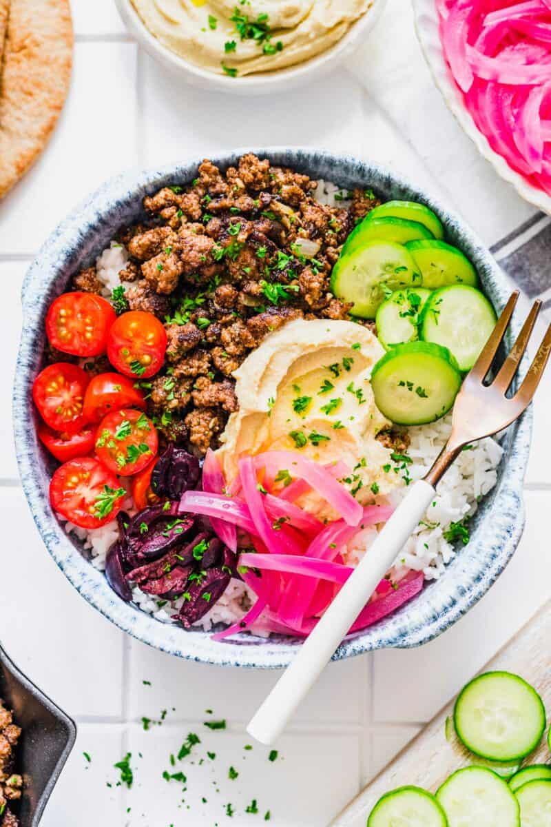 A ground beef bowl is presented on a white countertop with a fork. 