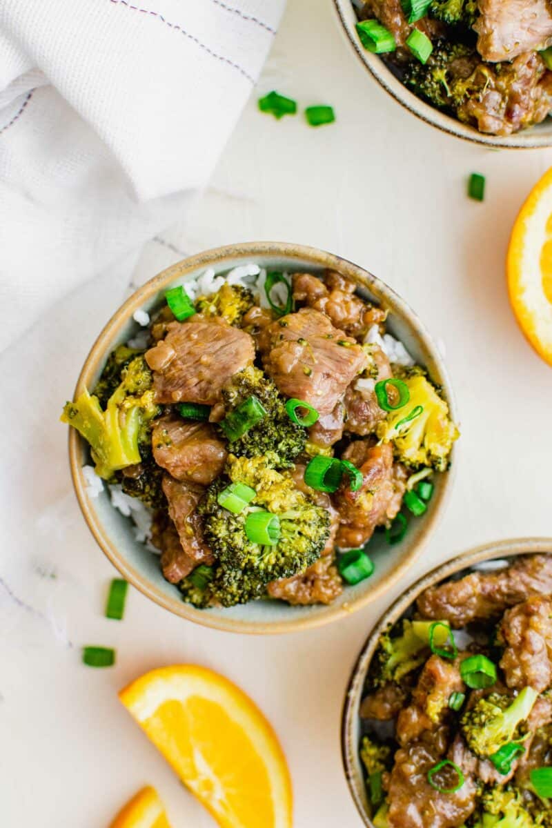 Two bowls are filled with rice, broccoli, and steak. 