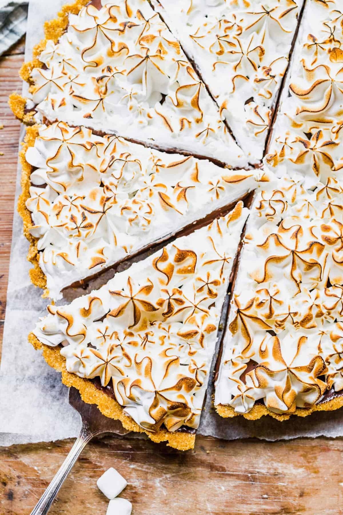 This s'mores tart recipe takes just 15 minutes to make! With a graham cracker crust, ganache filling, and toasty meringue, it's irresistible. Overhead view of sliced s'mores tart