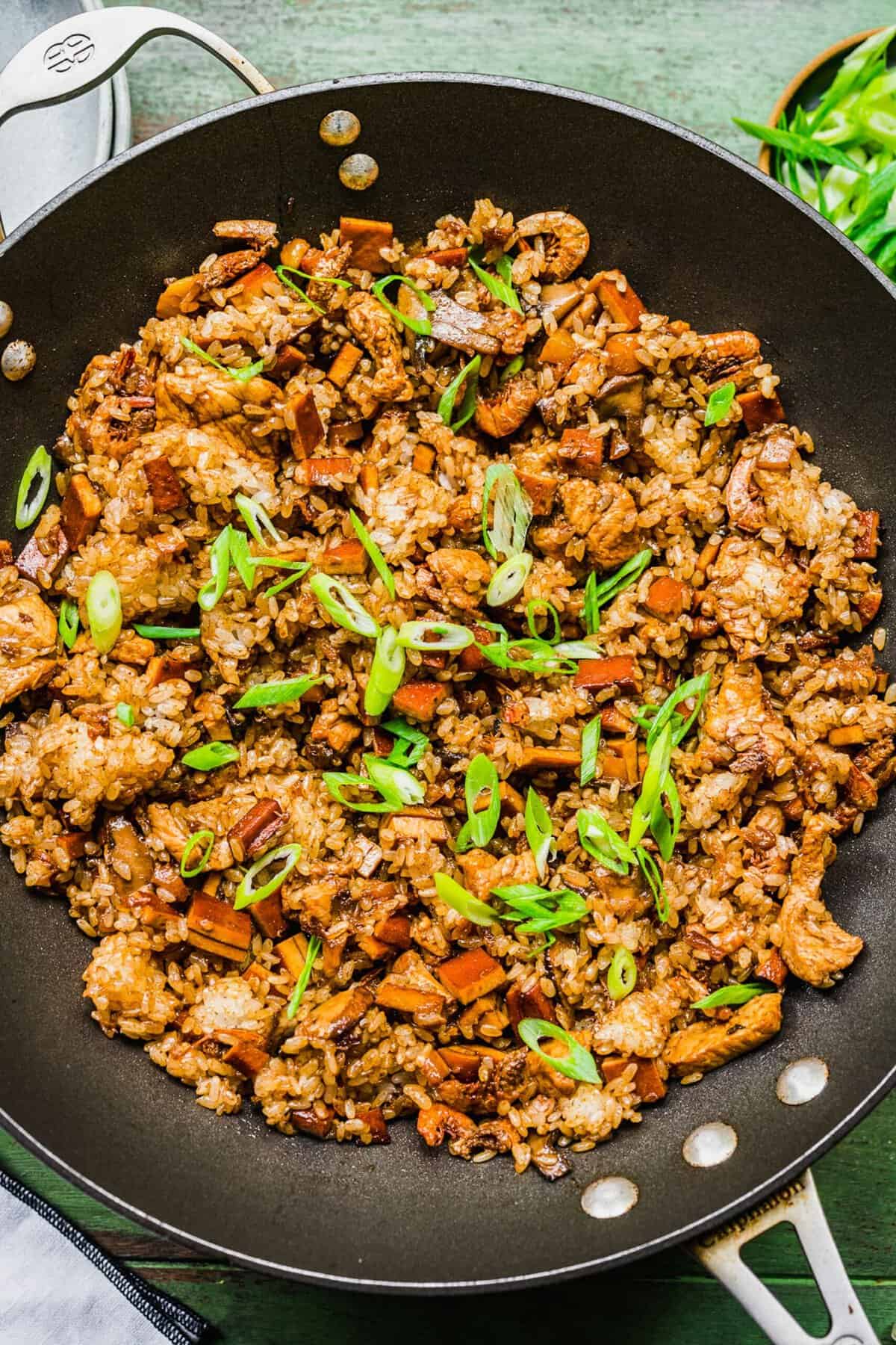 Sticky rice in skillet with sliced scallions