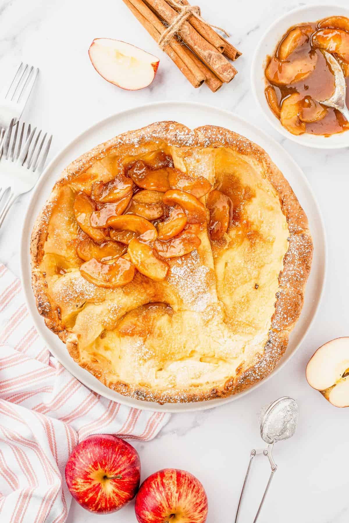 Fall table is set with an Apple Cinnamon Dutch Baby topped with apple compote in the center of table.