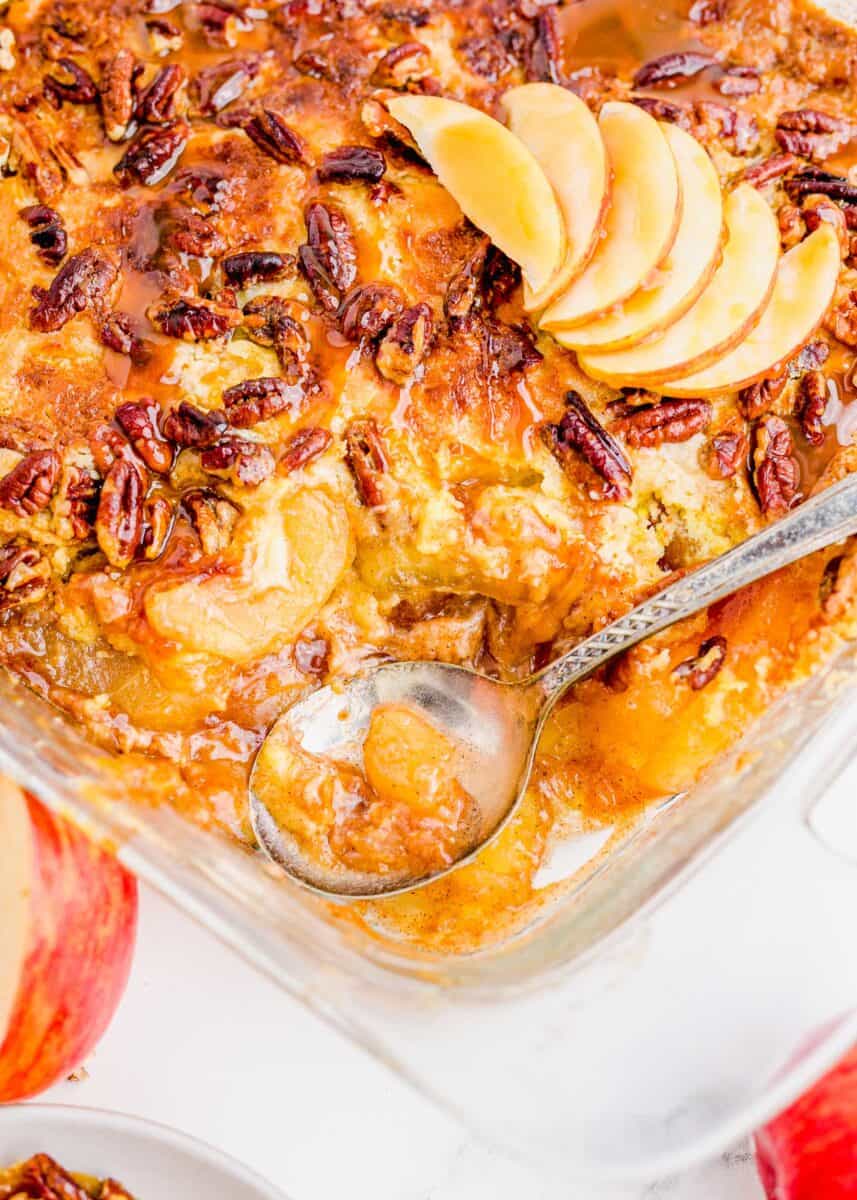 An antique silver serving spoon sits on top of freshly baked Caramel Apple Dump Cake. 