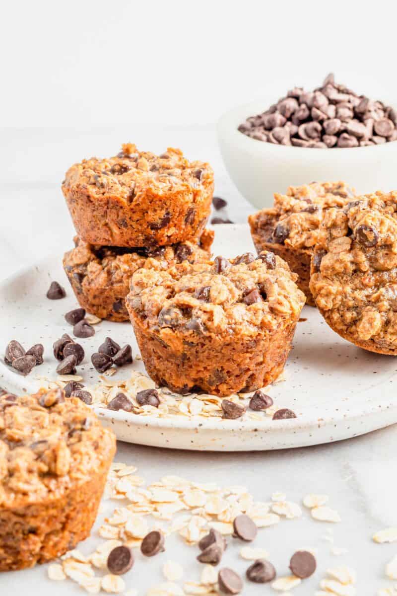 Chocolate chips and oats are spread out around some cookie cups. 