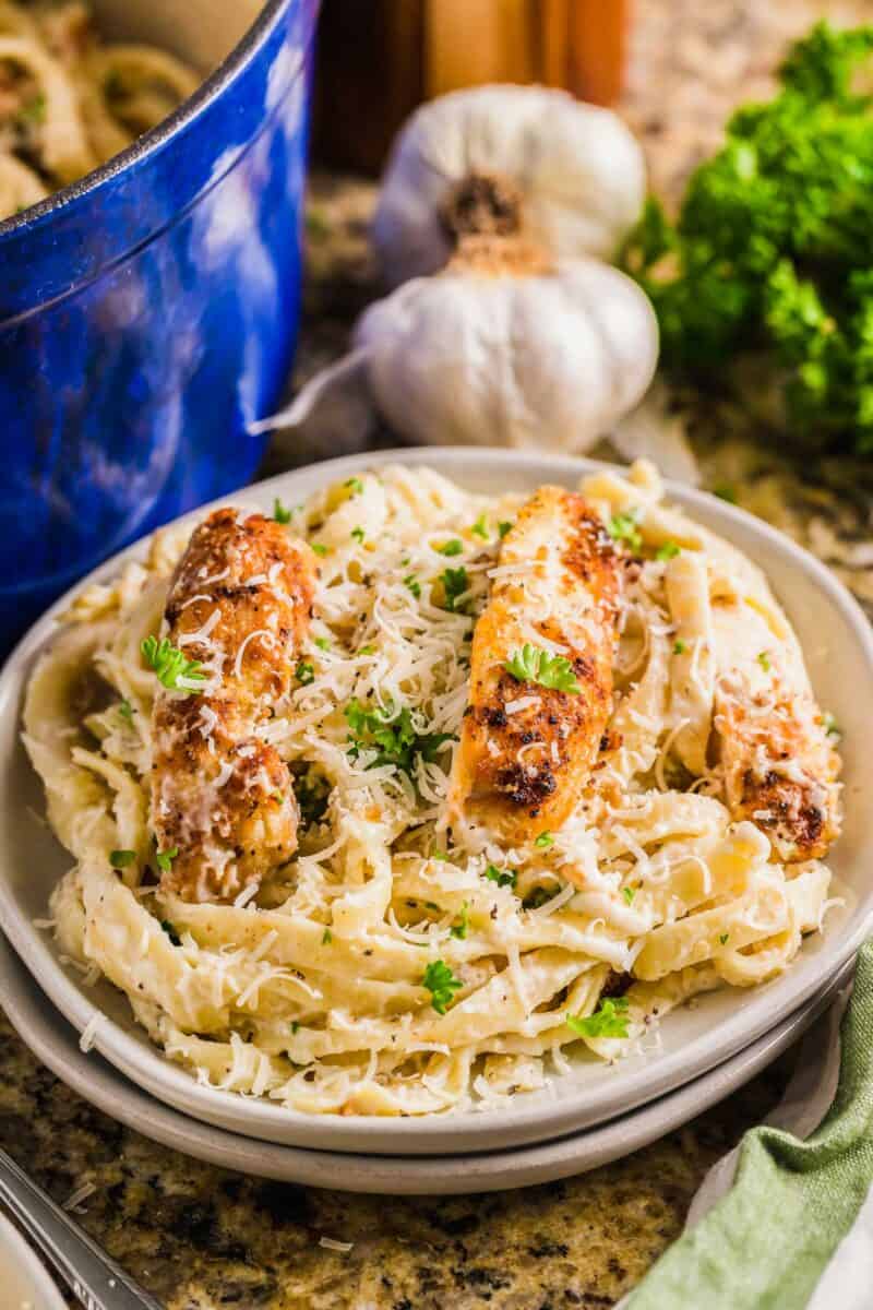 Parsley and parmesan garnish a plate filled with pasta and chicken. 