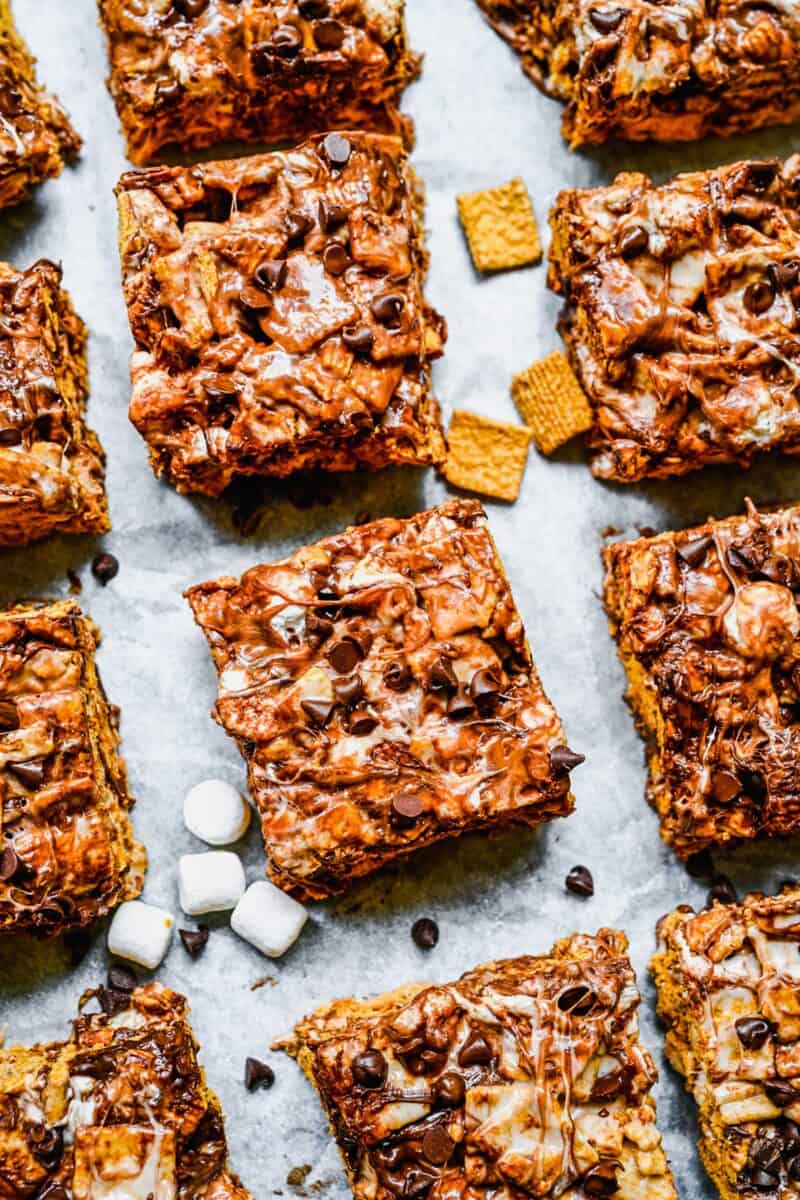 Perfectly portioned bars are placed next to each other on a surface with marshmallows and chocolate chips scattered around them. 