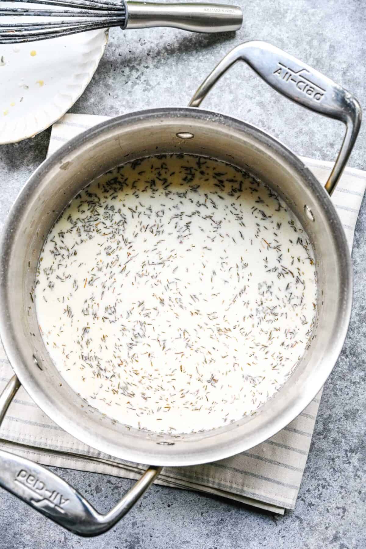 A pan filled with thickened milk, and dried thyme in it, on top of a kitchen towel