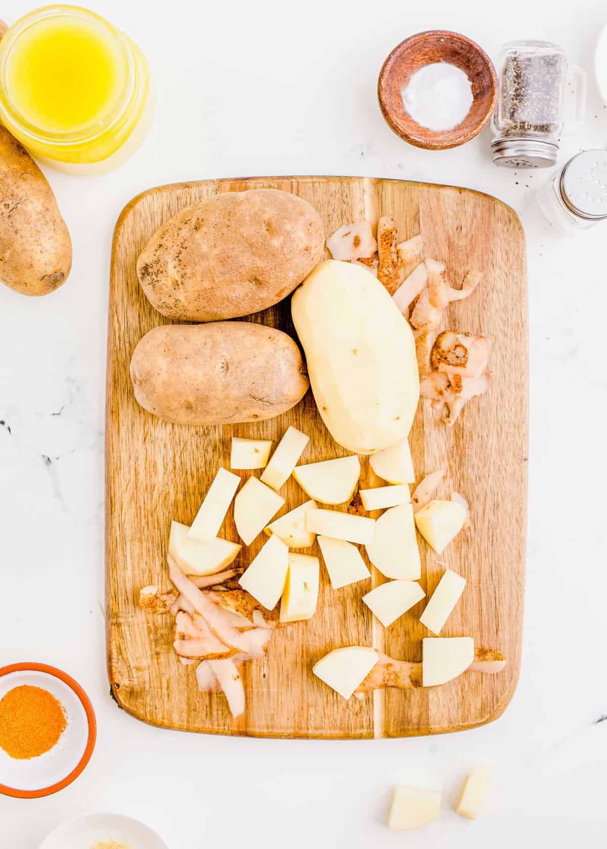 image of russet potatoes on a cutting board being cut into cubes