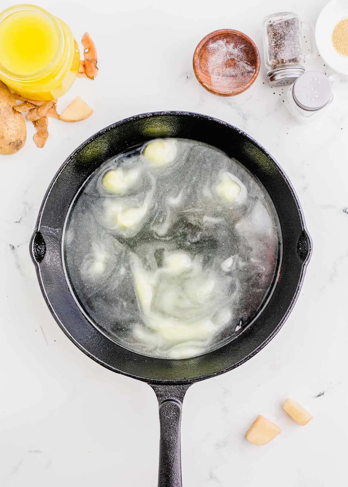 overhead shot of duck fat being melted in a cast iron skillet