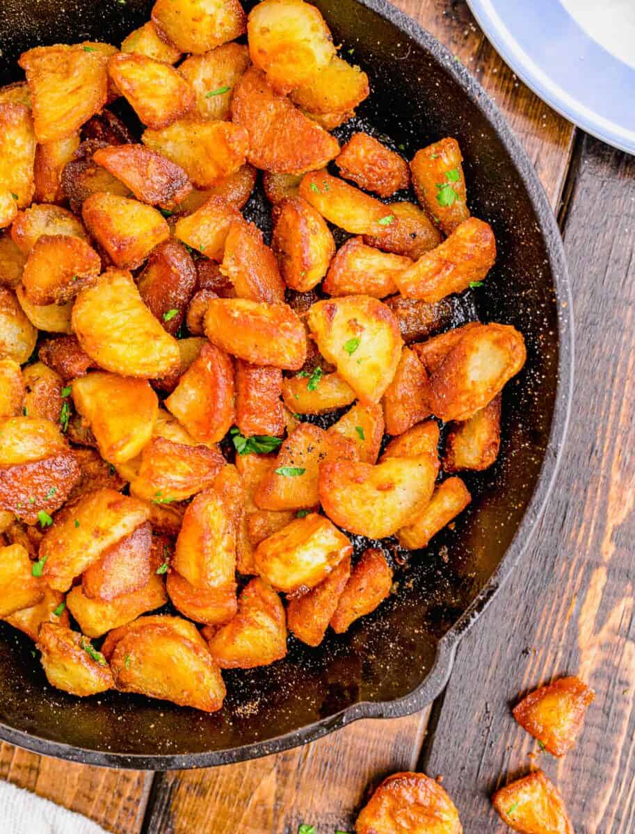 close up overhead shot of duck fat potatoes with a couple on the wooden background