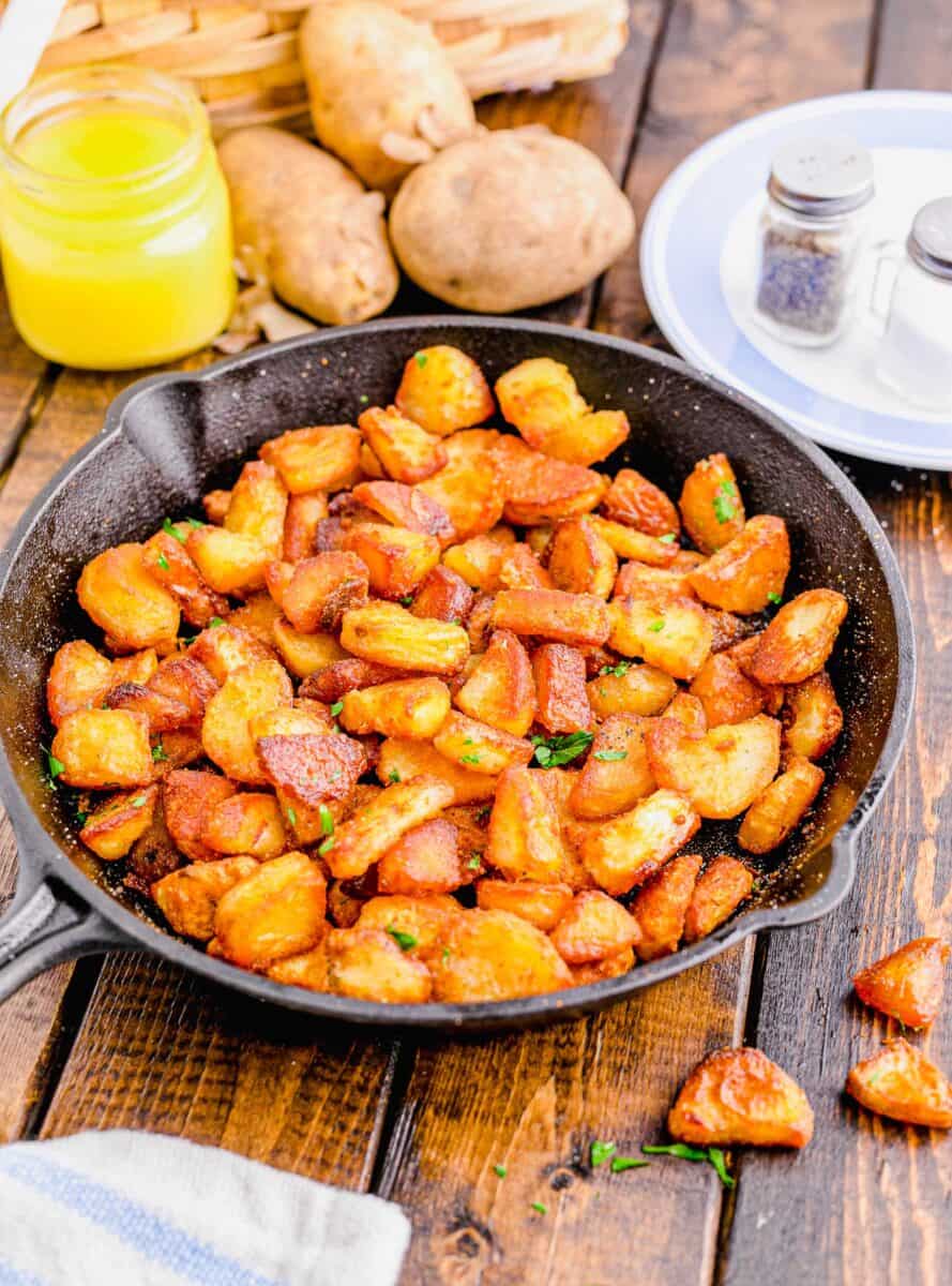 45 degree angle shot of crispy duck fat potatoes in a cast iron skillet