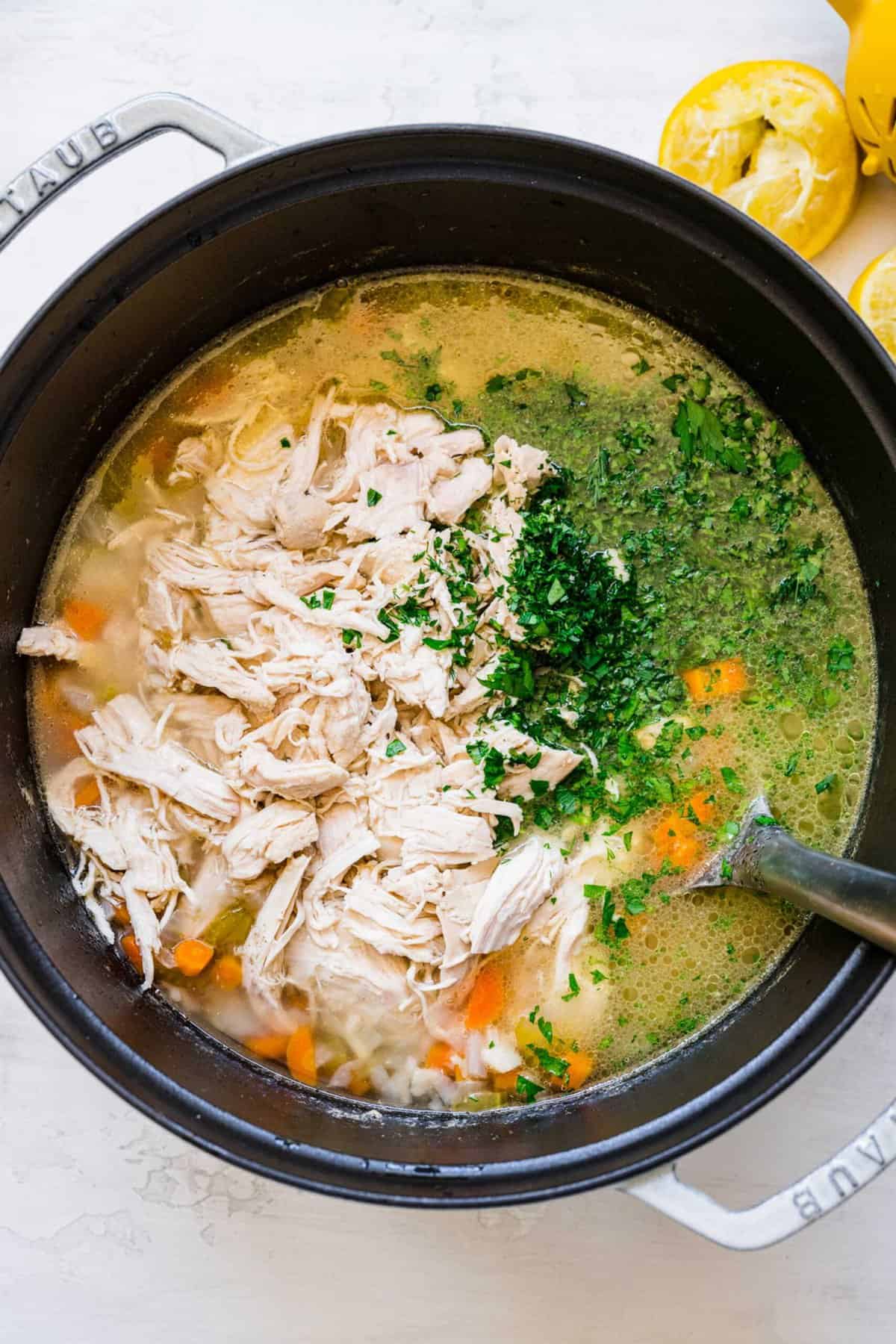 shredded chicken being added back in the large pot of soup