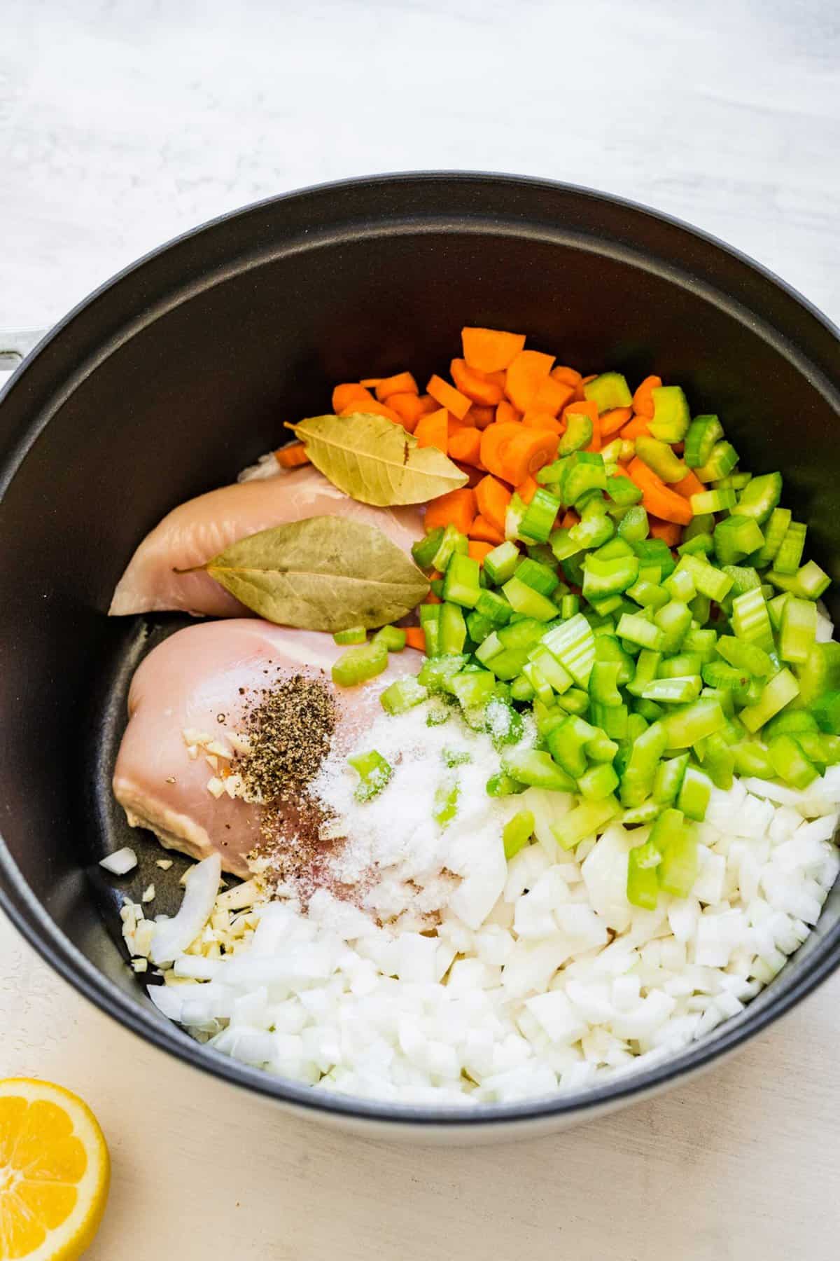 raw chicken, bay leaves, uncooked carrots, celery, onion, and seasonings in a large pot