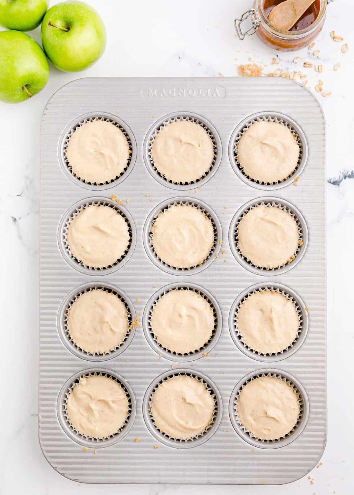 A 12-muffin muffin tray filled with uncooked cheesecake batter