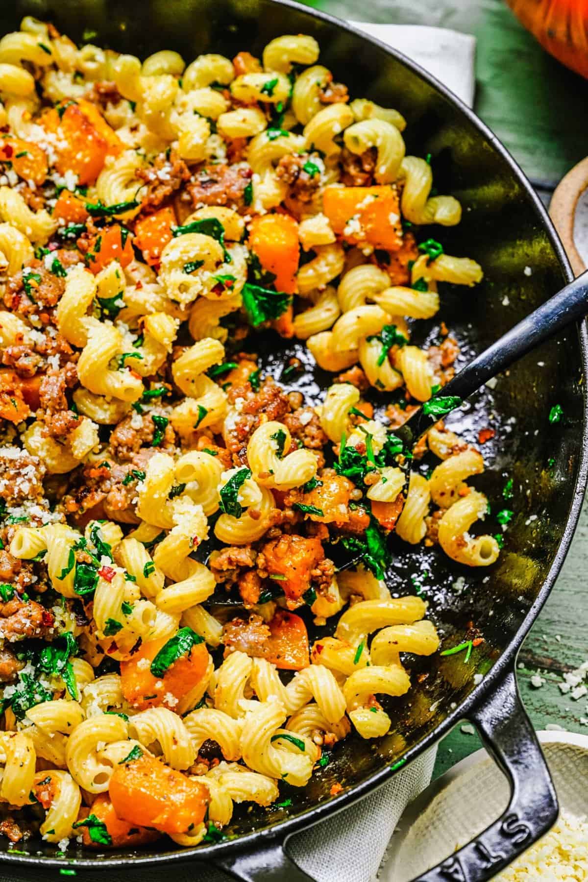 up close shot of pasta with pumpkin and sausage in the pot with a spoon