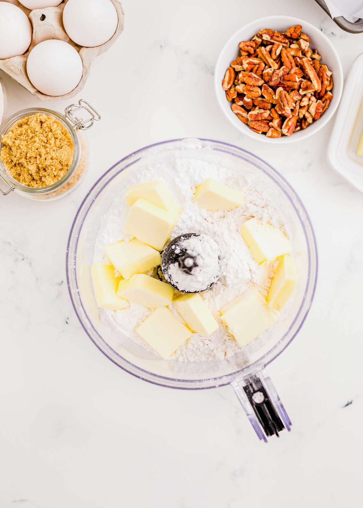 cubes of butter in a food processor with flour and powdered sugar