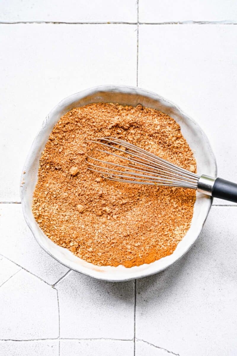 A bowl with pumpkin pie spice mixture, mixed together, with a whisk in it