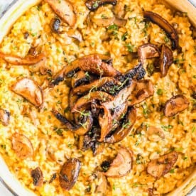 Overhead view of a pot of risotto, topped with mushrooms and parsley