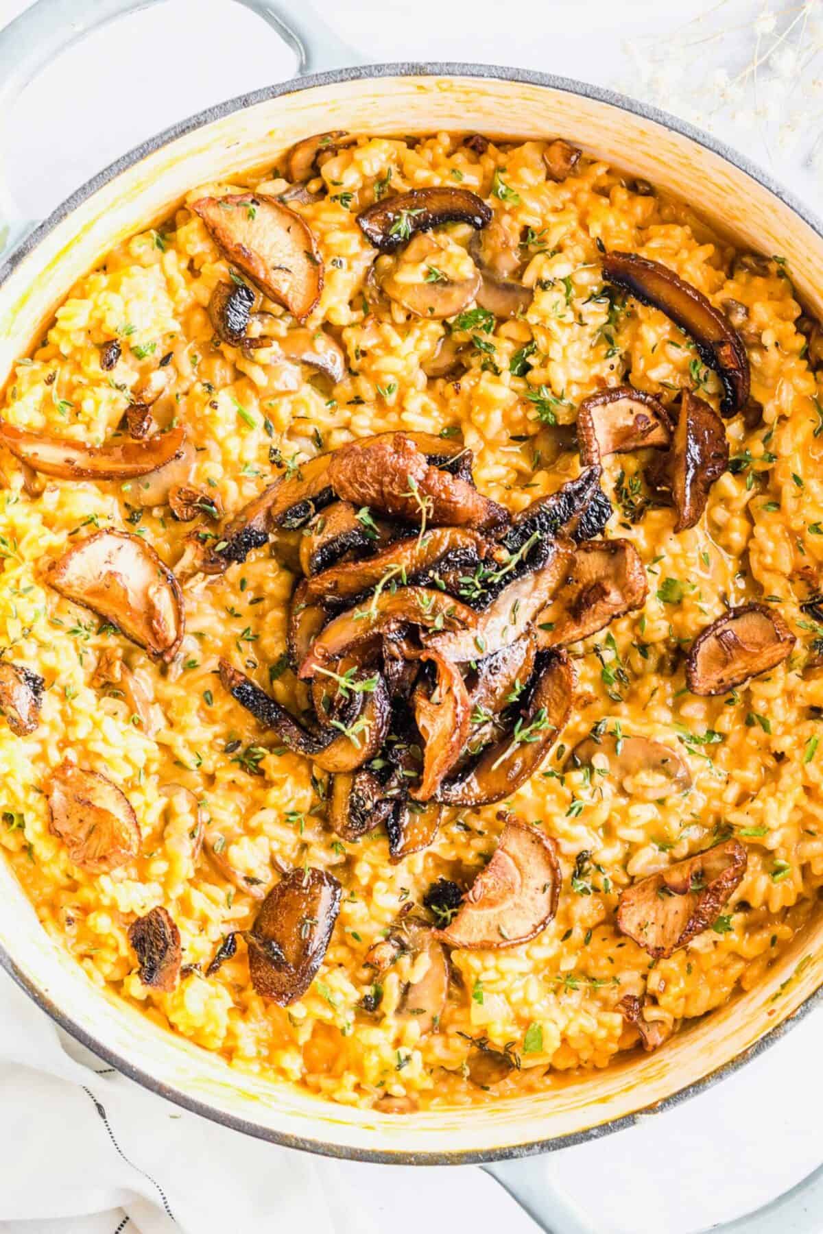 Overhead view of a pot of risotto, topped with mushrooms and parsley
