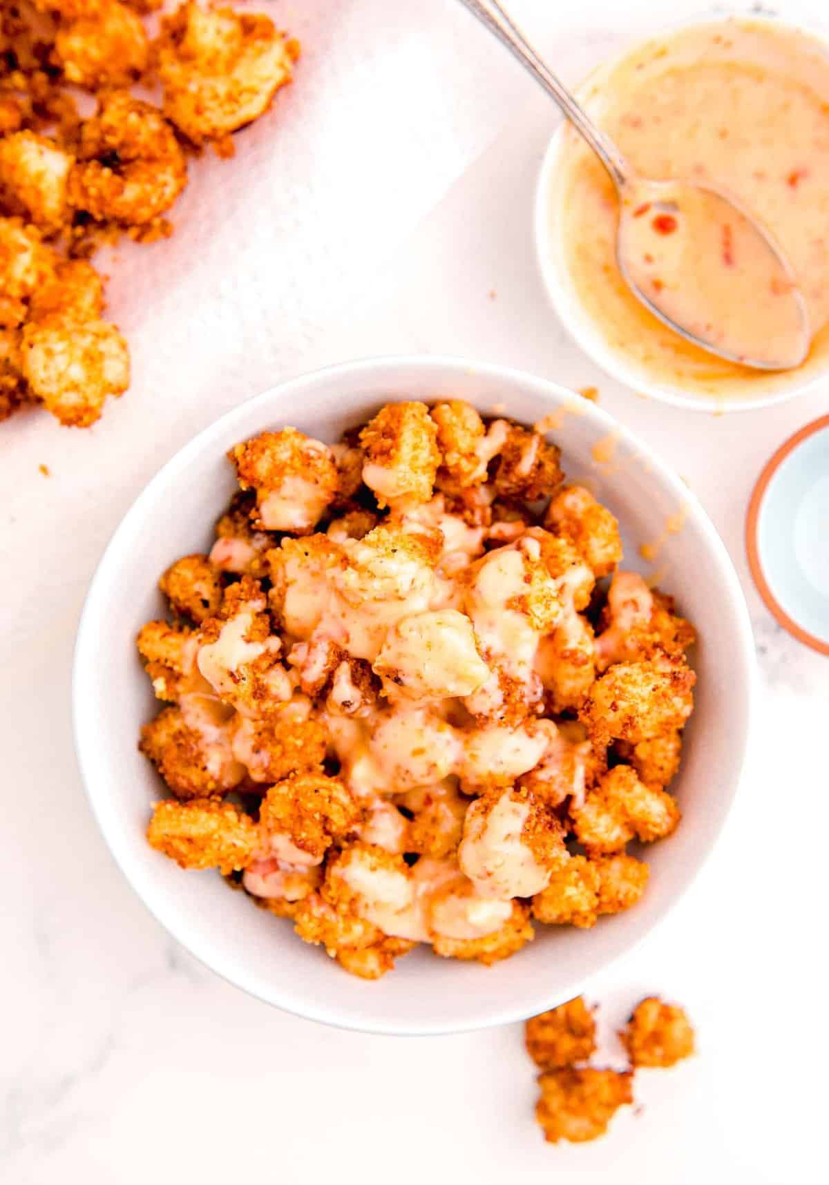 the mayo mixture is added on top of the bowl with the fried shrimp