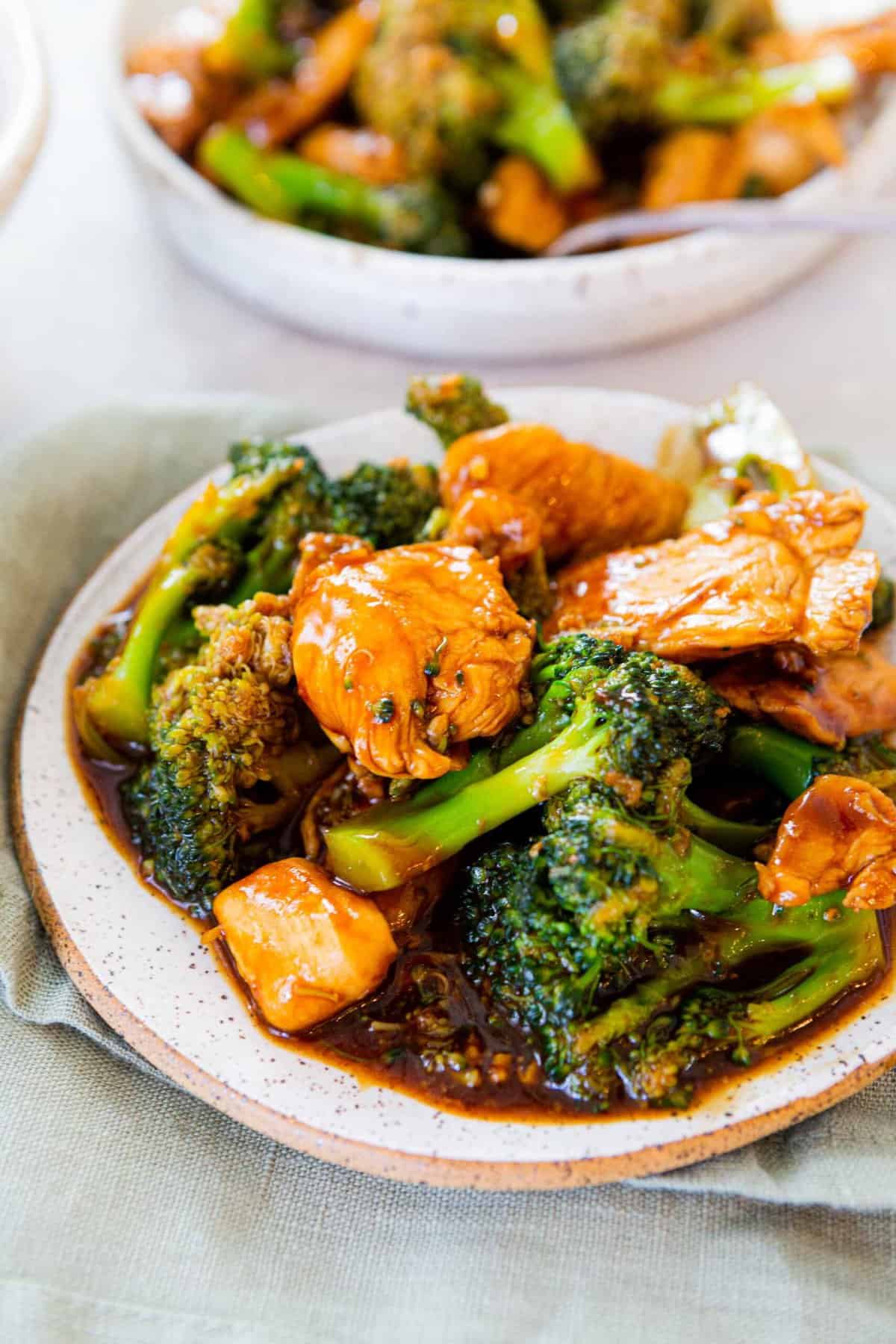 chinese chicken and broccoli with dark brown sauce on a speckled white plate