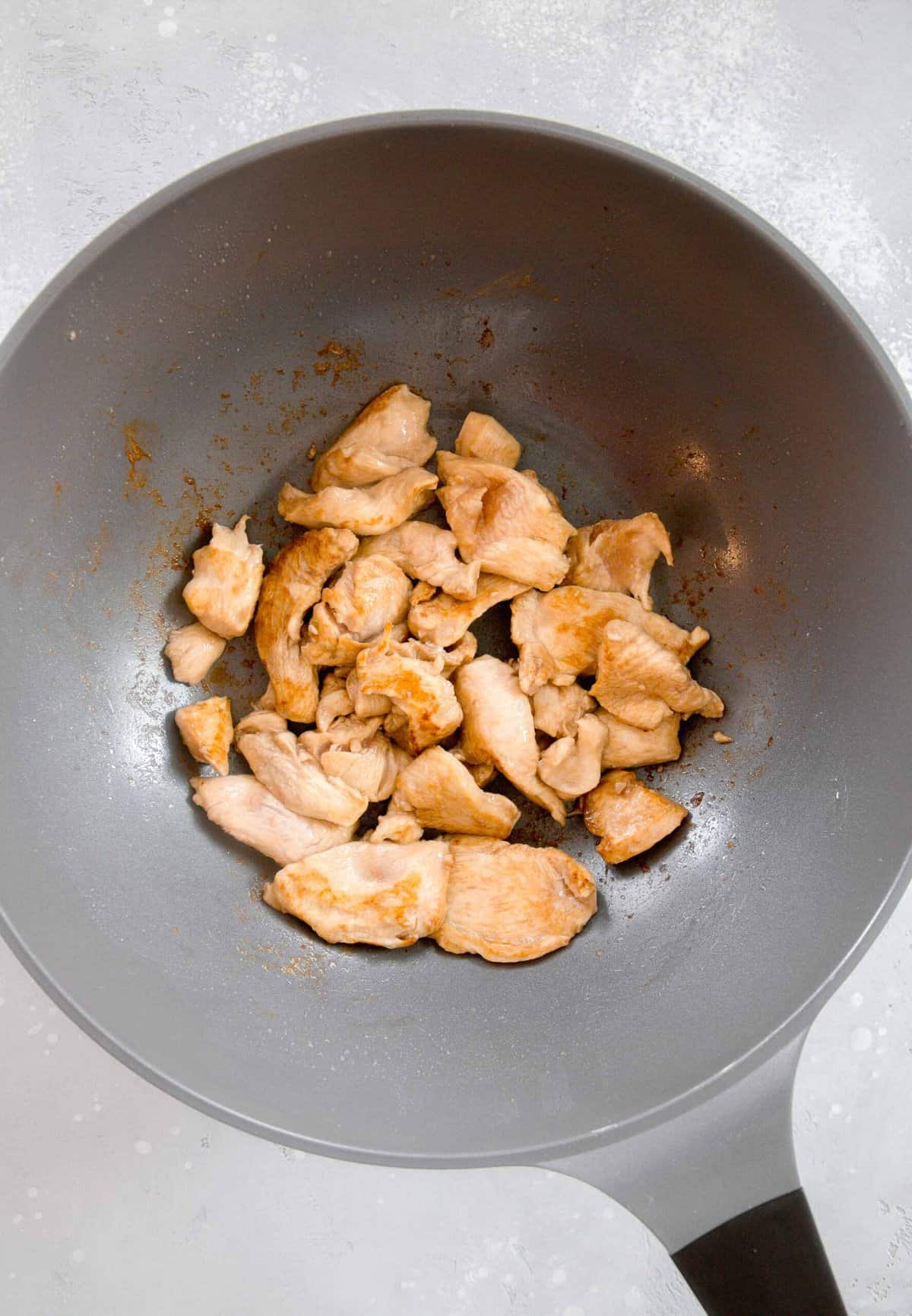 thin slices of boneless skinless chicken breast being browned in a large wok