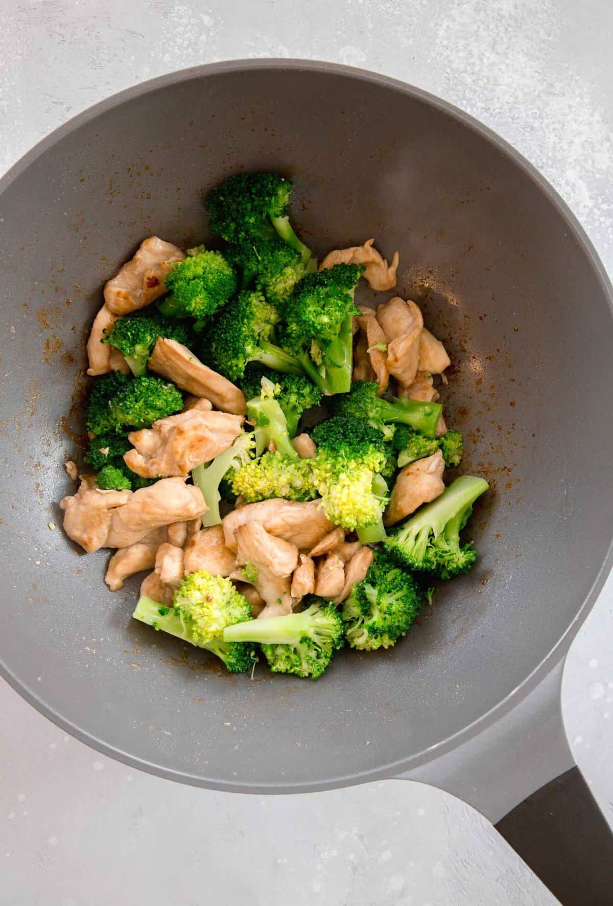 broccoli florets added to the wok along with the browned chicken