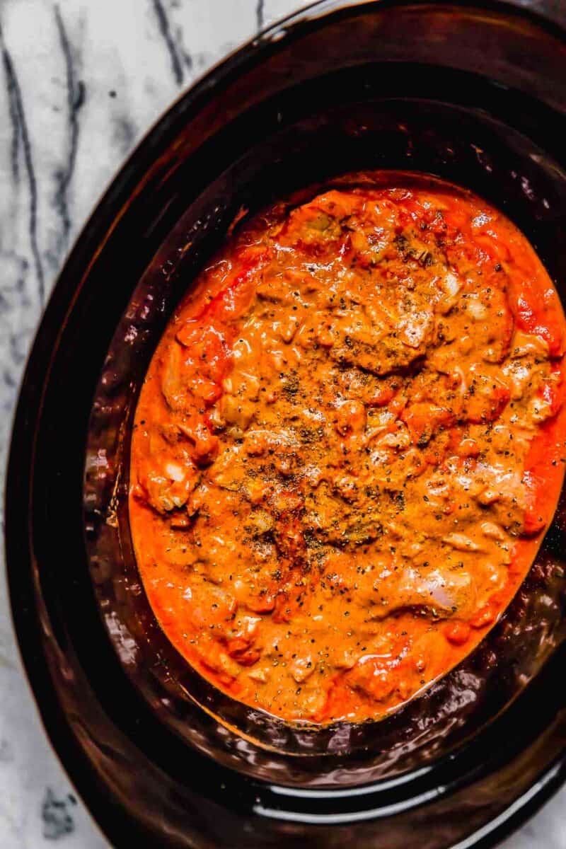chicken tikka masala mixture in the insert of a slow cooker with seasonings on top