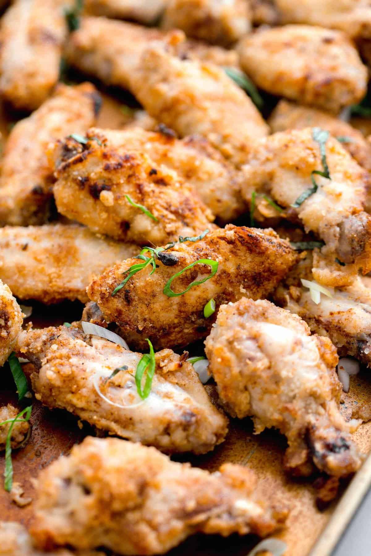 chinese salt and pepper chicken on a large baking sheet with fresh basil and scallions sprinkled on top