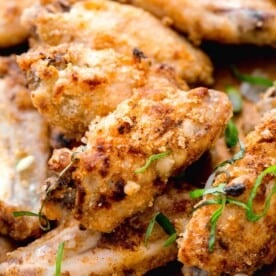 up close shot of a chinese salt and pepper chicken flat wing to show crispy crust. fresh basil and scallions can be seen sprinkled on top