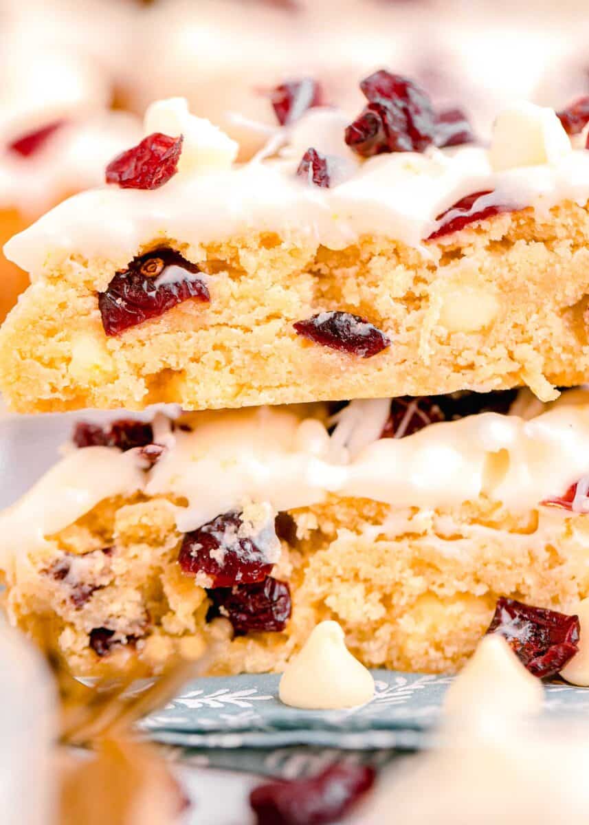 side image of cranberry bliss bars with large pieces of dried cranberry and white chocolate in the shortbread base