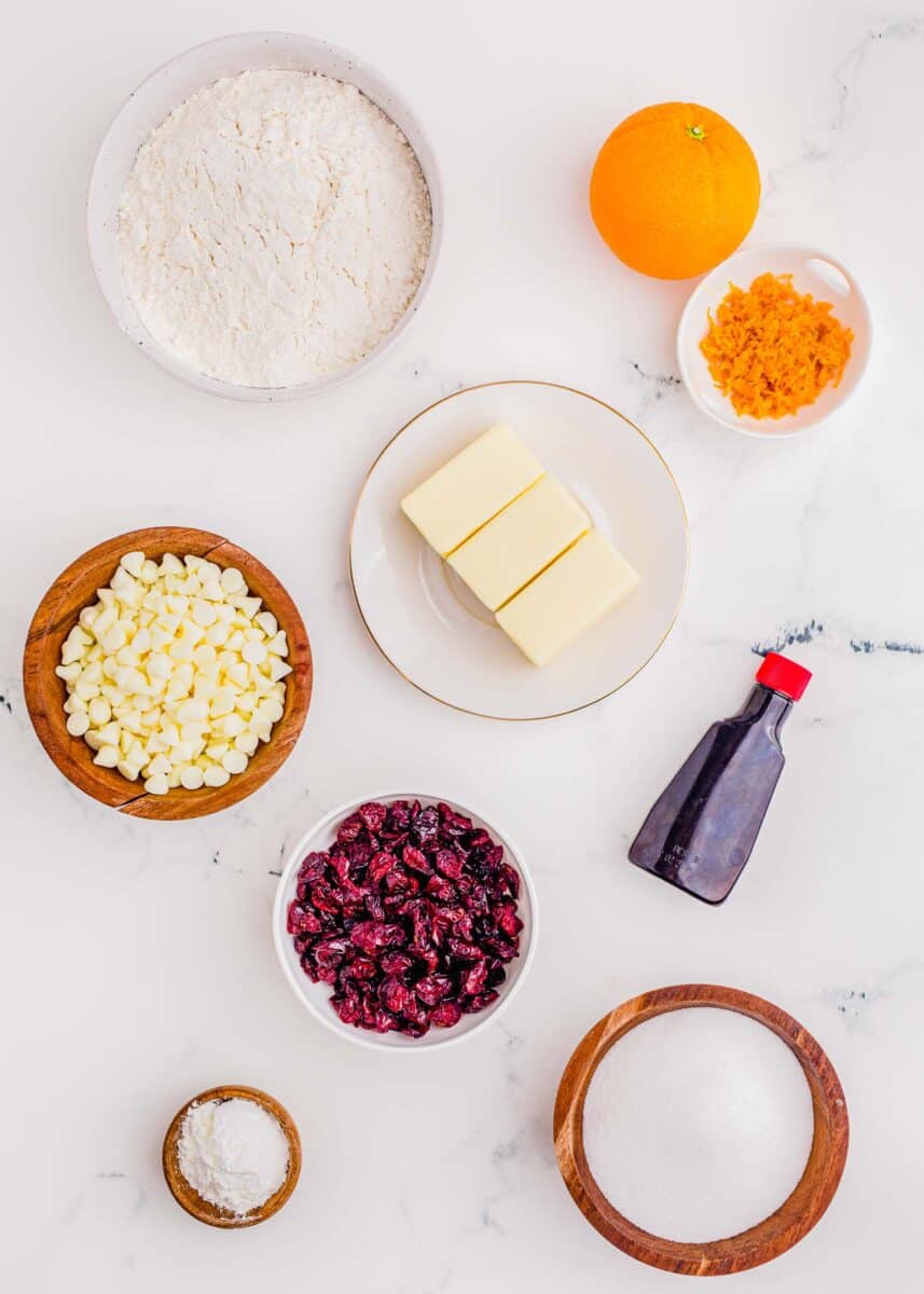 ingredients for cranberry orange shortbread cookies: flour, butter, orange zest, almond extract, sugar, cornstarch, dried cranberries, and white chocolate chips