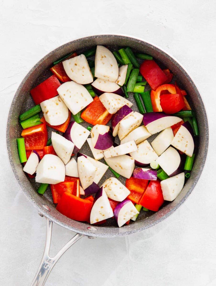 eggplant, red bell pepper, and scallions added to the skillet