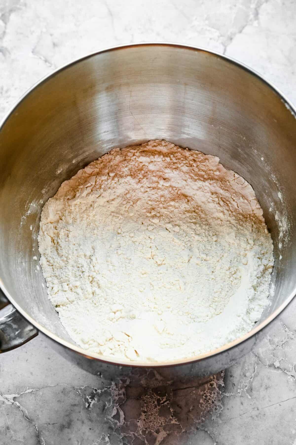 A stand mixer mixing bowl filled with a flour mixture