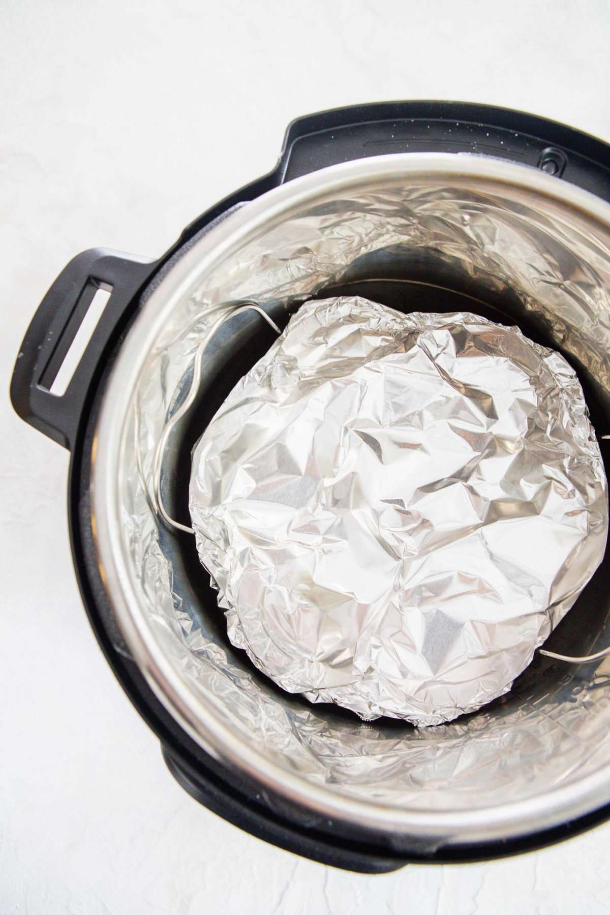 egg molds covered in aluminum foil on a metal rack in the insert of an instant pot