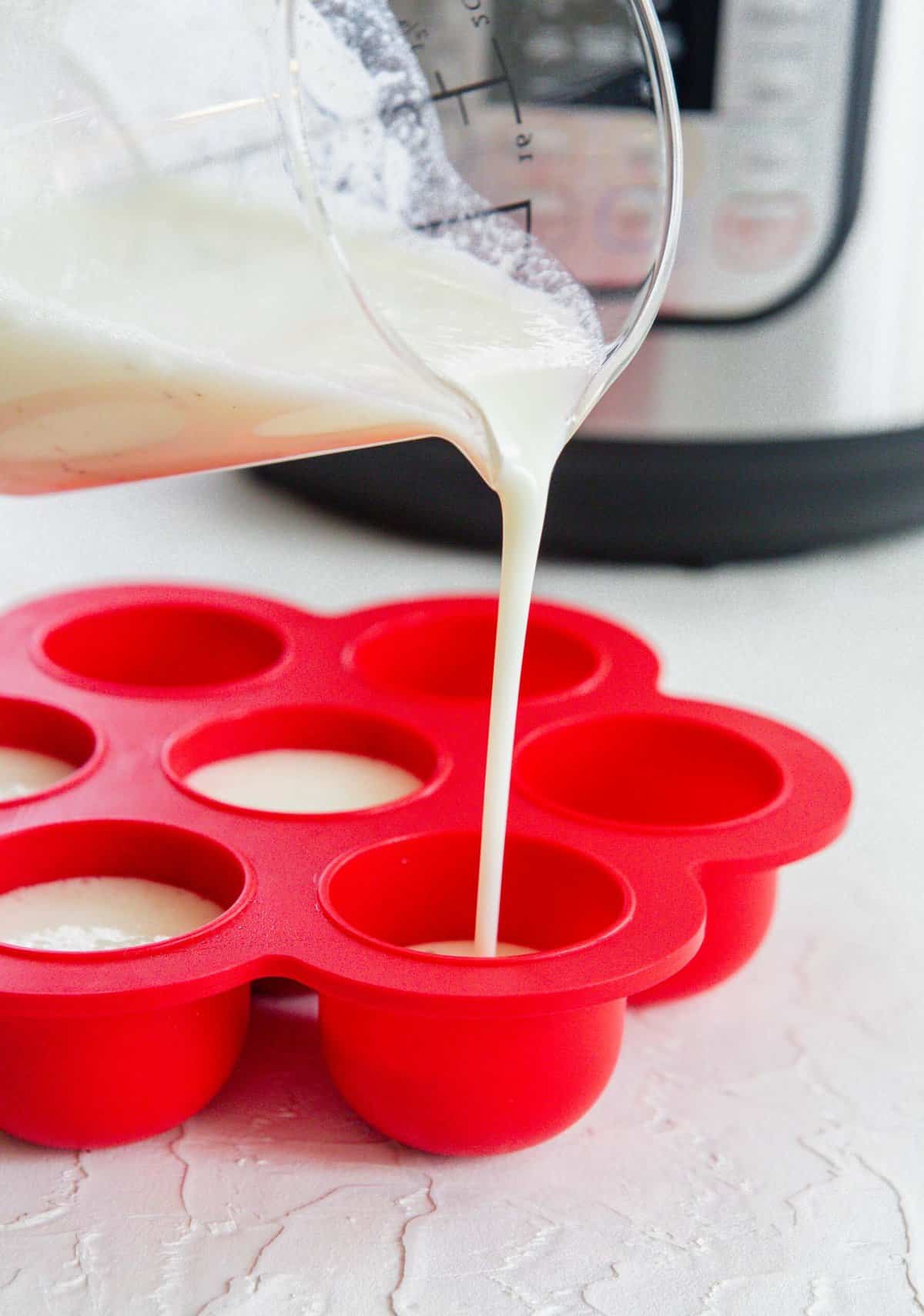 pouring egg white mixture into a red silicone egg mold next to an instant pot