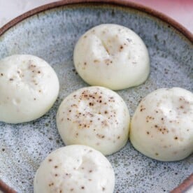 up close image of egg white egg bites on a speckled blue plate. the egg white bites have ground pepper spots on top